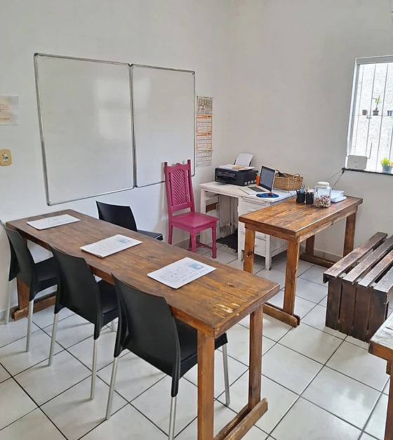 Sala de aula do Ateliê de Palavras organizada, com mesas de madeira, quadro branco e cantinho de estudos preparado para os atendimentos